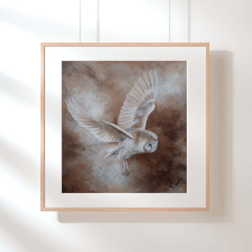 Framed wall art featuring a painted owl in flight, shown hanging on a white wall with soft shadows. The artwork has a white mat and a light natural wood frame.