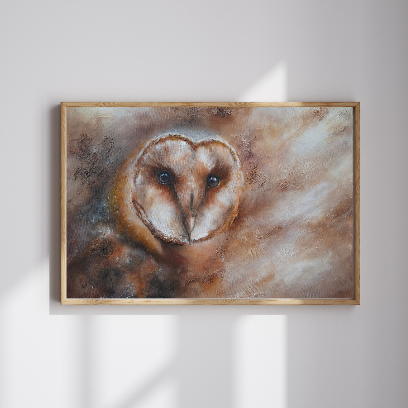 A framed painting of a barn owl with a heart-shaped face, displayed on a light gray wall with soft window shadows.