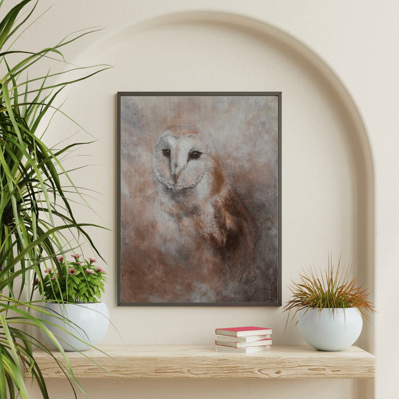 A framed art print of a barn owl with a textured, painterly brown and beige background, displayed on a light wood shelf in a styled interior setting with potted plants.